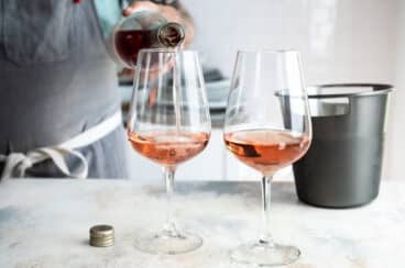 Somebody pouring two glasses of rose wine.