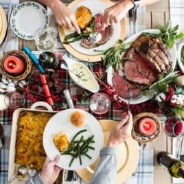 A Christmas table with prime rib, scalloped potatoes, green beans, and rolls.