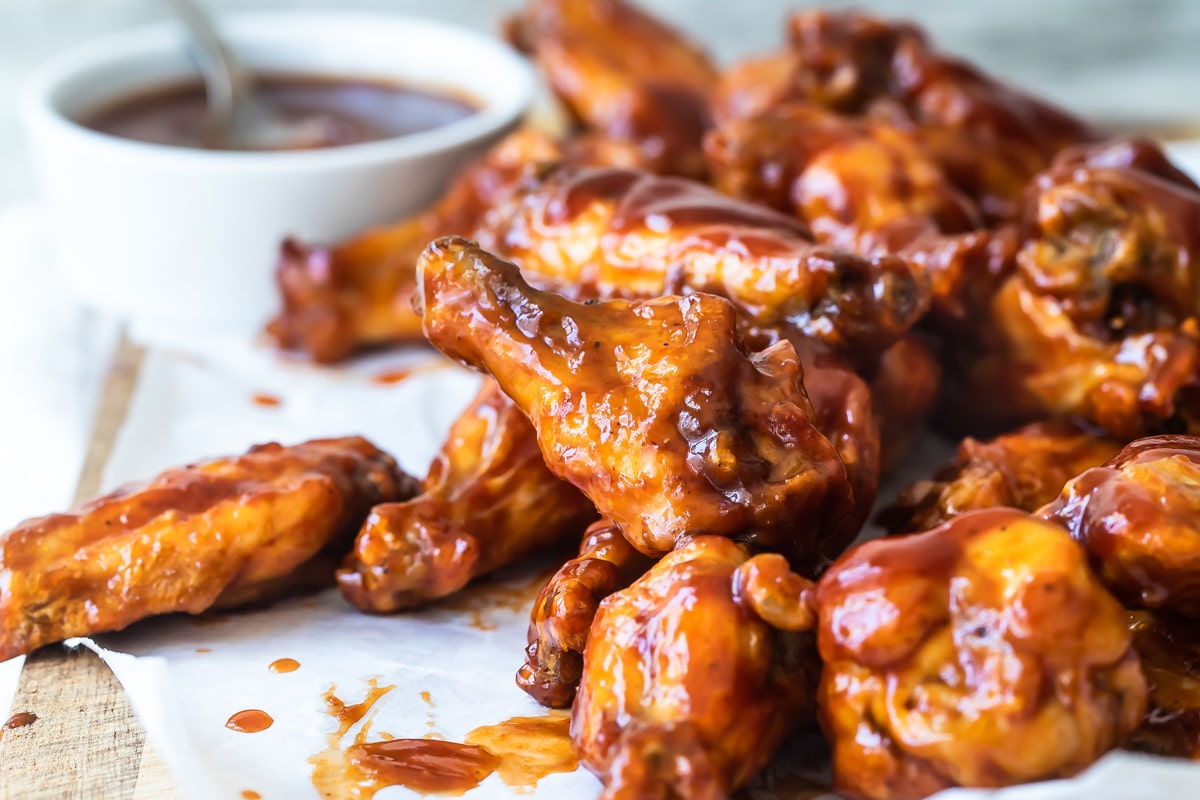 Air fryer chicken wings covered in barbecue sauce on a wooden cutting board.
