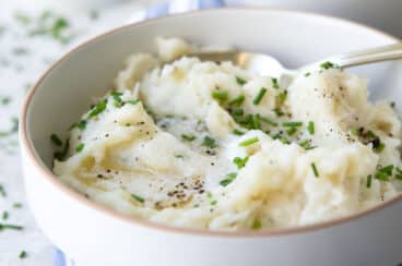 A bowl of air fryer mashed potatoes garnished with chives.