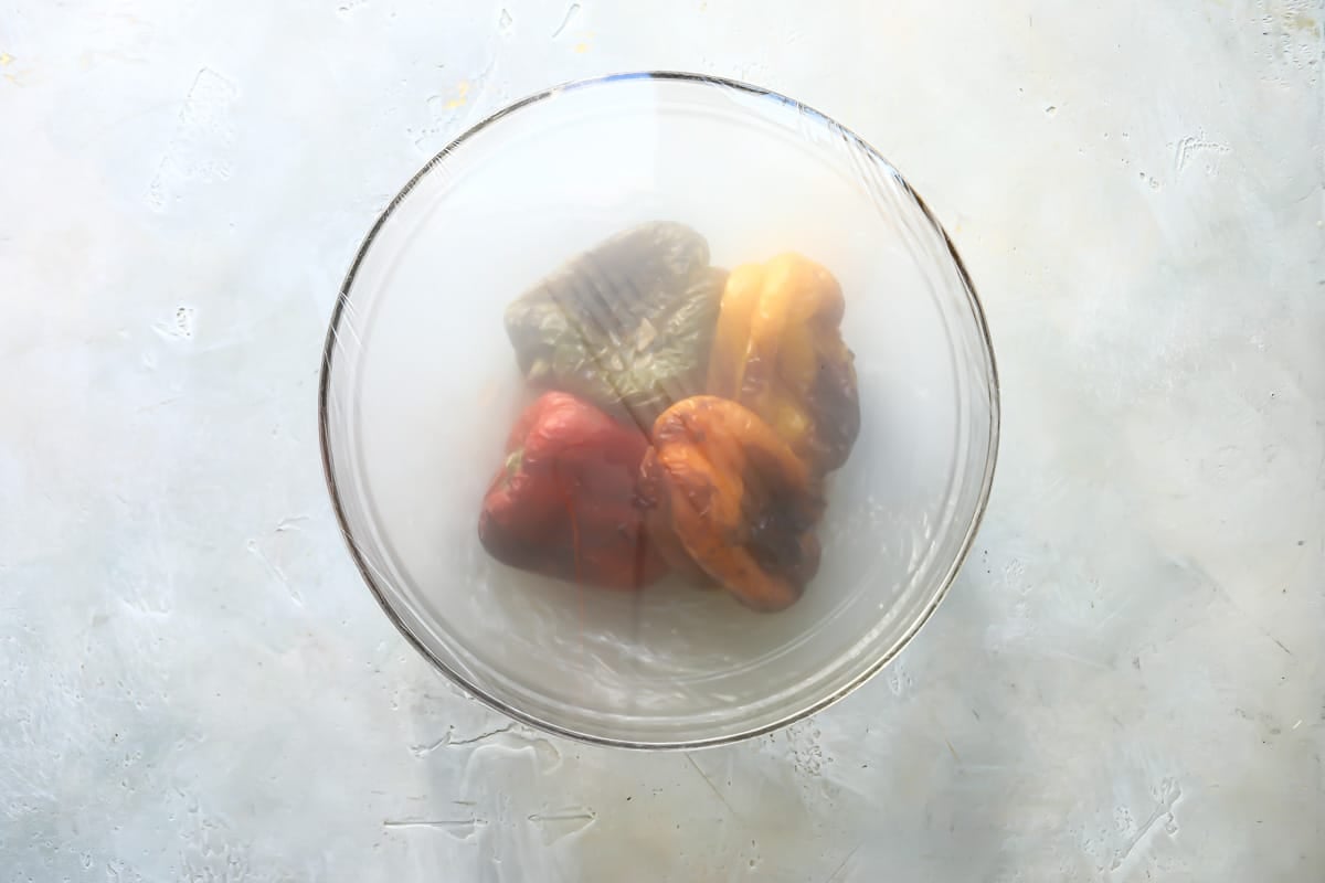 Air fried peppers in a clear bowl covered in plastic wrap.