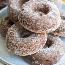 Seven apple cider donuts on a gray round plate.