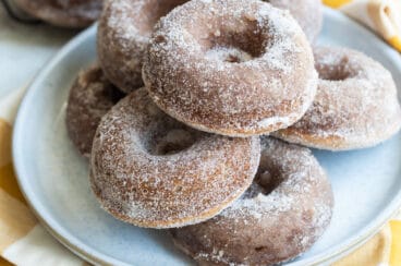 Seven apple cider donuts on a gray round plate.