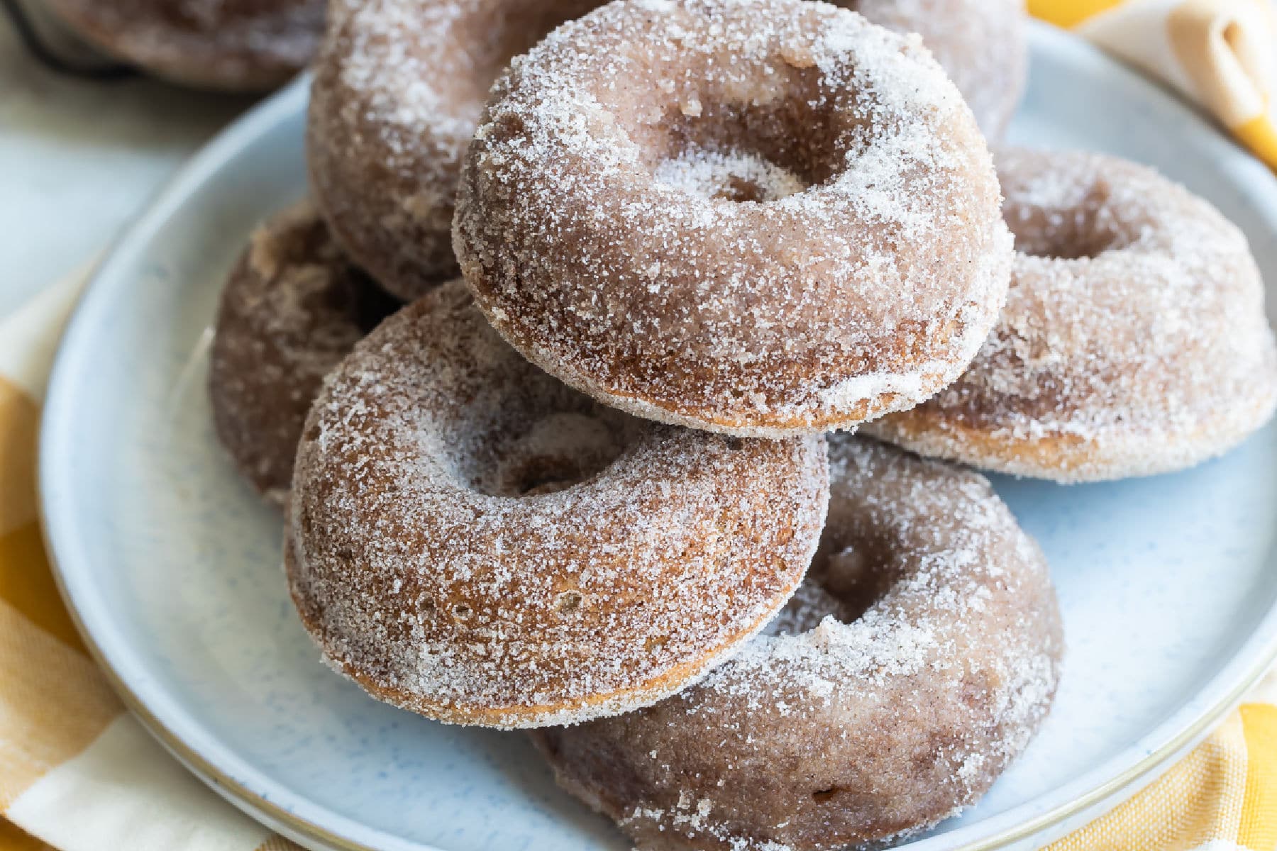 Seven apple cider donuts on a gray round plate.