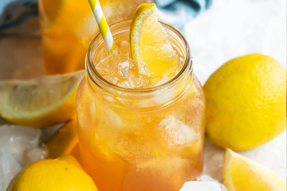 An arnold palmer in a mason jar with a lemon wedge garnish.