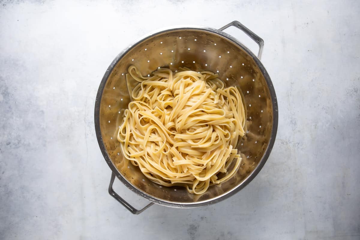 A colander full of cooked fettuccine.