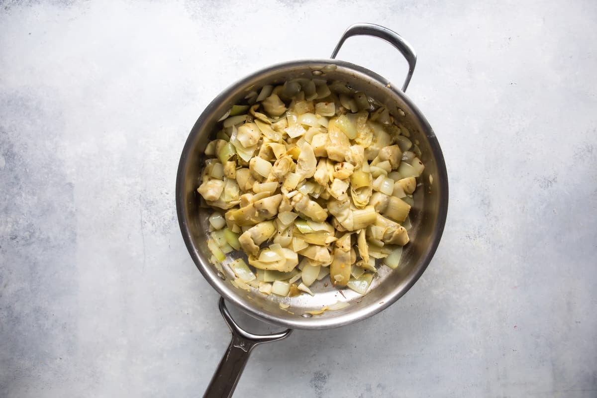 Cooking artichoke hearts in a skillet.