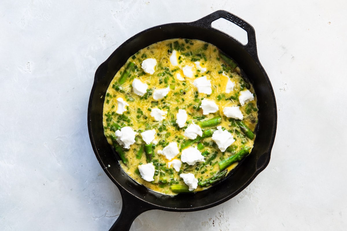 Asparagus fritatta before being cooked in a cast iron skillet.