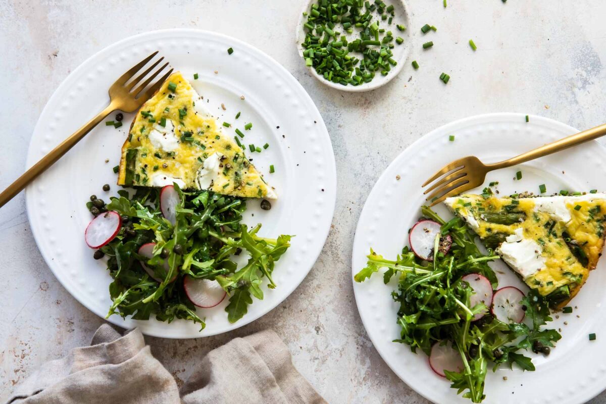 Two slices of asparagus fritatta on white plates.