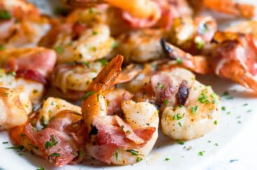 Bacon wrapped shrimp on a white platter.