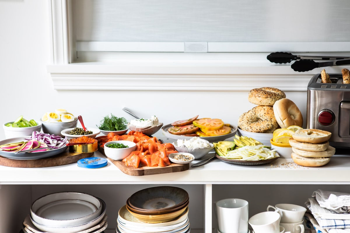 A Bagel Bar stocked with bagels, smoked salmon, cream cheese, avocado, tomatoes, watermelon radishes, cucumbers, caviar, and fresh herbs and spices.