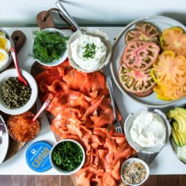 A Bagel Bar stocked with bagels, smoked salmon, cream cheese, avocado, tomatoes, watermelon radishes, cucumbers, caviar, and fresh herbs and spices.
