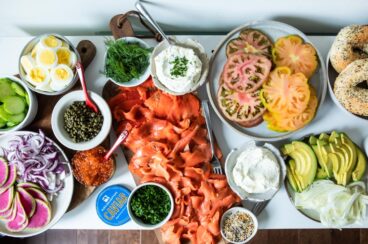 A Bagel Bar stocked with bagels, smoked salmon, cream cheese, avocado, tomatoes, watermelon radishes, cucumbers, caviar, and fresh herbs and spices.