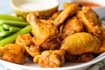 Baked buffalo wings on a white platter.