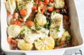 Baked cod in a white baking dish.