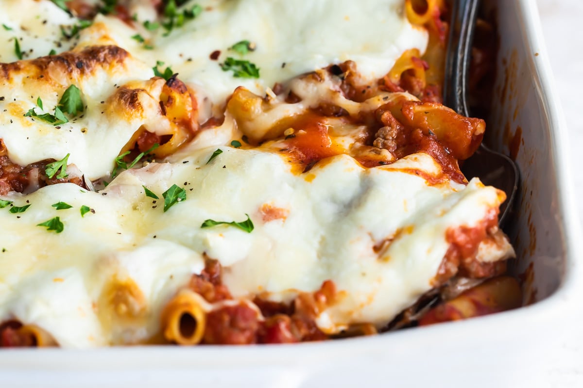 A pan of baked ziti with a spoon in it.