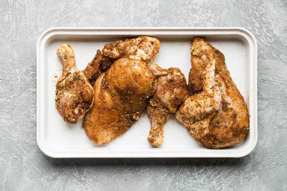 raw chicken quarters on a platter.