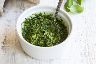 A bowl of pesto with a spoon in it.