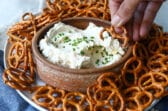 A bowl of beer cheese dip surrounded by pretzels.