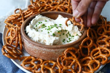 A bowl of beer cheese dip surrounded by pretzels.