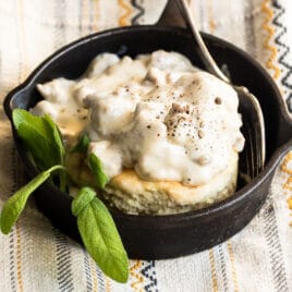 Biscuits and gravy in a small black skillet.