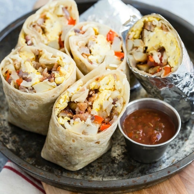 Breakfast burritos cut in half on a sliver tray.