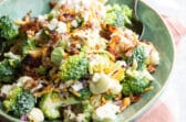Broccoli salad with bacon and cheese in a green bowl.