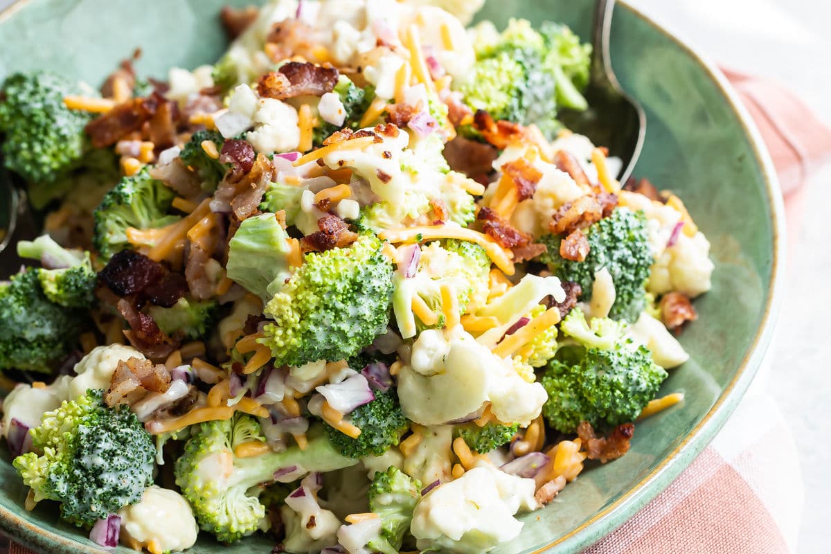 Broccoli salad with bacon and cheese in a green bowl.