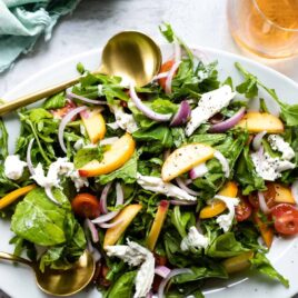 A platter of burrata salad with peaches.