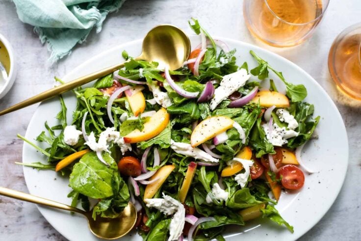 A platter of burrata salad with peaches.