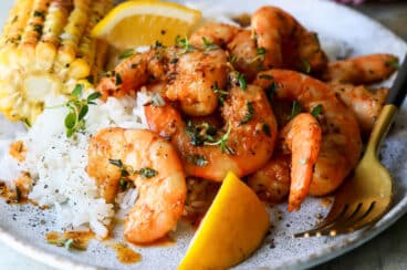 A plate of cajun shrimp, white rice, and corn on the cob.