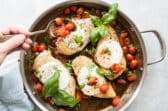 Caprese chicken in a stainless steel skillet.