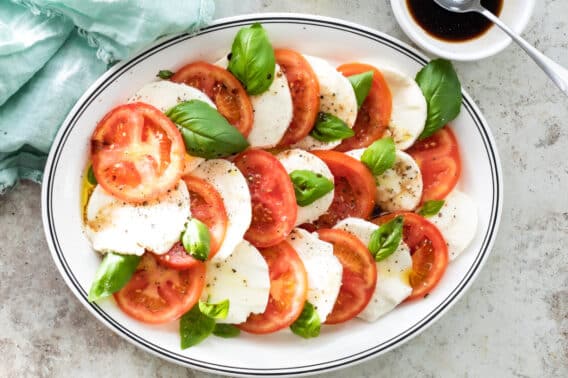 Caprese salad on a white serving dish with a blue rim.