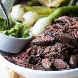 Carne Asada on a serving platter with grilled vegetables.