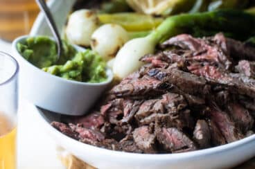 Carne Asada on a serving platter with grilled vegetables.