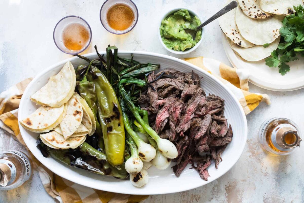 Carne Asada on a serving platter with grilled vegetables.