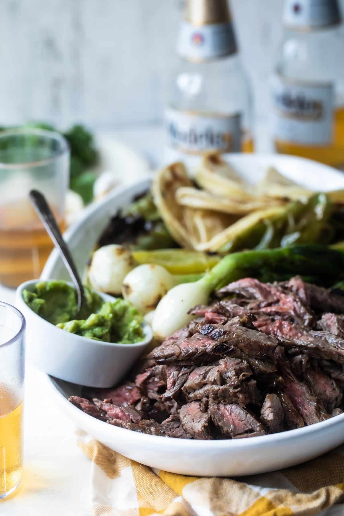 Carne Asada on a serving platter with grilled vegetables.