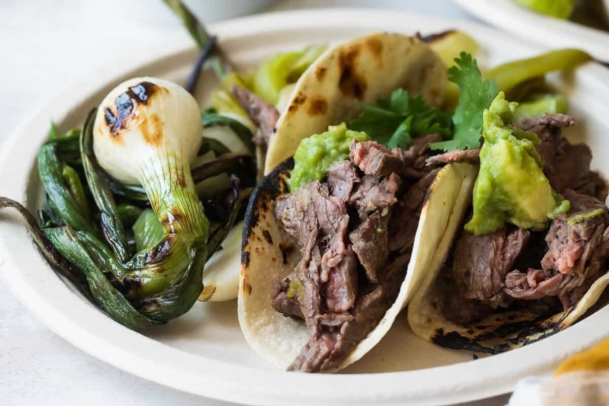 Carne Asada on a paper plate with grilled vegetables.