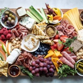 A charcuterie board filled with meats, cheese, fruits, nuts, crackers, and other snacks.
