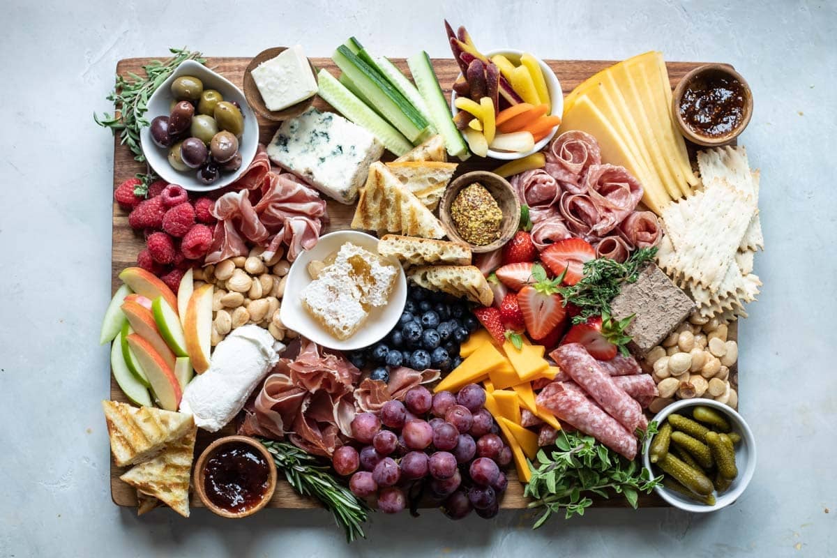 A charcuterie board filled with meats, cheese, fruits, nuts, crackers, and other snacks.