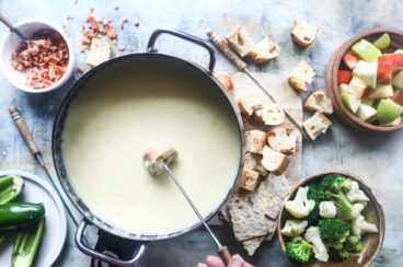A piece of bread being dipped in cheese fondue.
