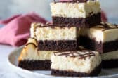 A stack of cheesecake brownies on a platter.