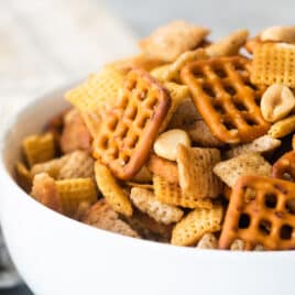 A bowl of Chex mix on a gray background.