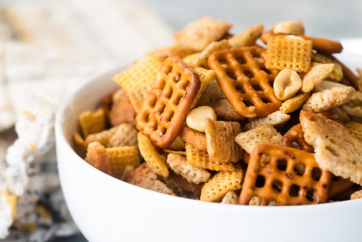 A bowl of Chex mix on a gray background.