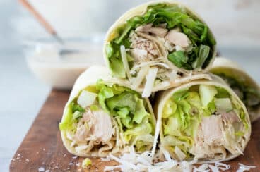 A board full of Chicken Caesar Wraps sliced in half.