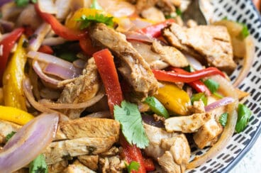 Chicken fajitas on a blue and white serving platter.