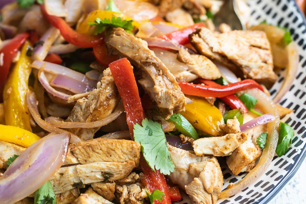 Chicken fajitas on a blue and white serving platter.