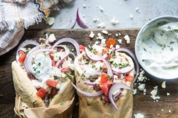 Two chicken gyros on a wooden cutting board.