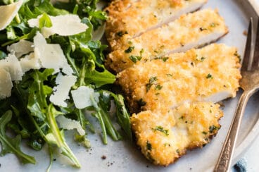 Chicken Milanese on a gray plate with a side of greens.