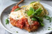 Chicken Parmesan plated with spaghetti.